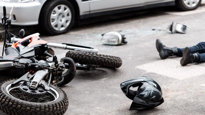 A person lying in the road after a motorcycle accident.