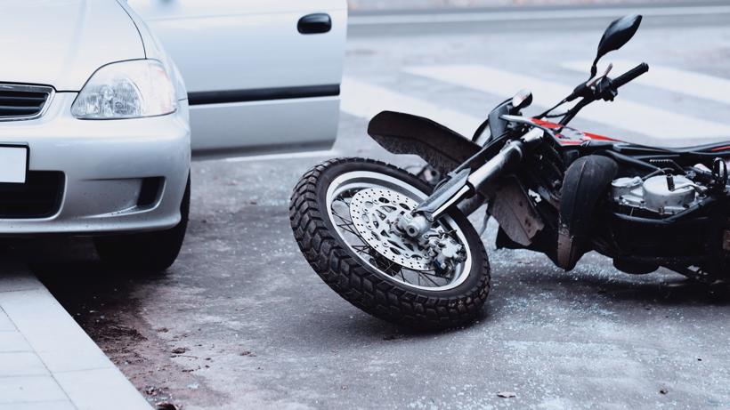 A motorcycle lying on the ground after being struck by a car.