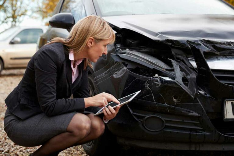 A lady accessing the damage of a vehicle that has been wrecked.