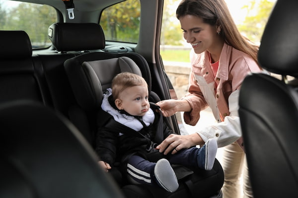 A mother smiles at a baby on board in a car.
