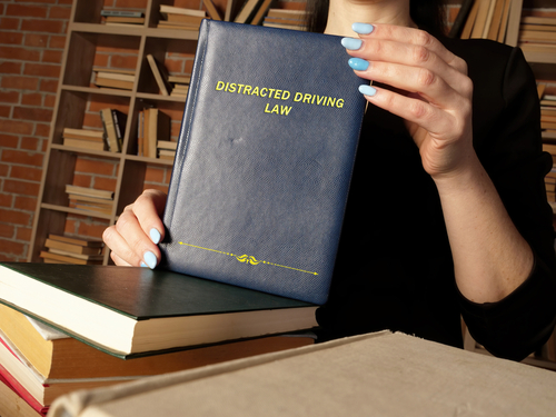 Distracted Driving Accident Lawyer holding a book on distracted law in a library dedicated to law.