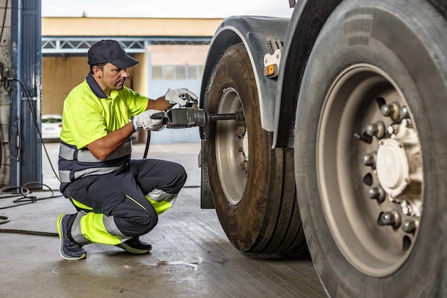 Mechanic inspecting the brake system of a commercial truck highlighting the importance of proper fleet maintenance