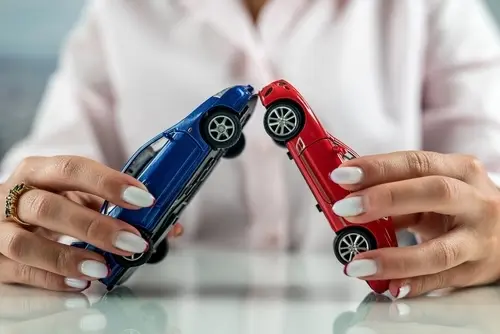 Understanding Liability in Multi-Vehicle Collisions Woman holding to colliding two cars together to represent a multi-vehicle collision case.