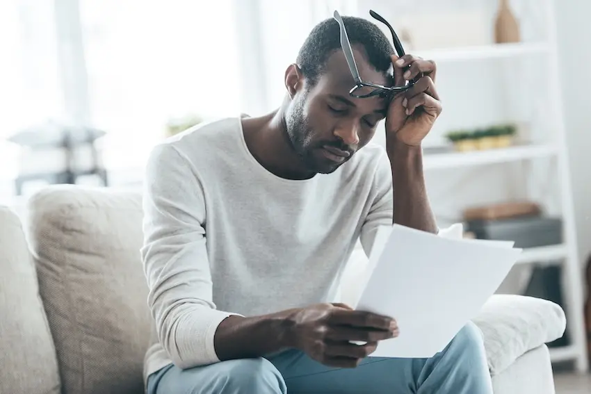 What tactics do insurance companies use to reduce your car accident payout in Georgia? Georgia car accident victim reviewing a lowball insurance settlement offer at home representing the insurance tactic cases handled by Wade Law Fayetteville car accident lawyers